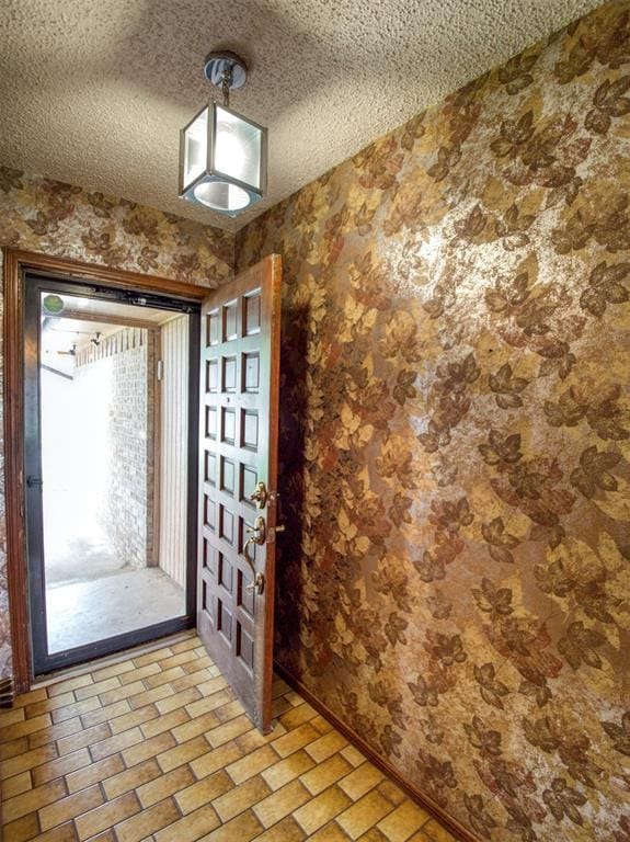 1520 NE 2nd St, Moore, OK 73160 - foyer featuring baseboards, wallpapered walls, a textured ceiling, and brick floor
