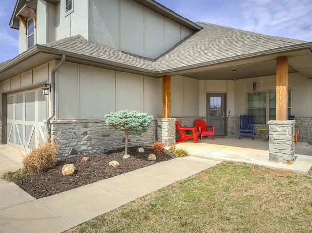 doorway to property featuring board and batten siding, a porch, roof with shingles, stone siding, and driveway
