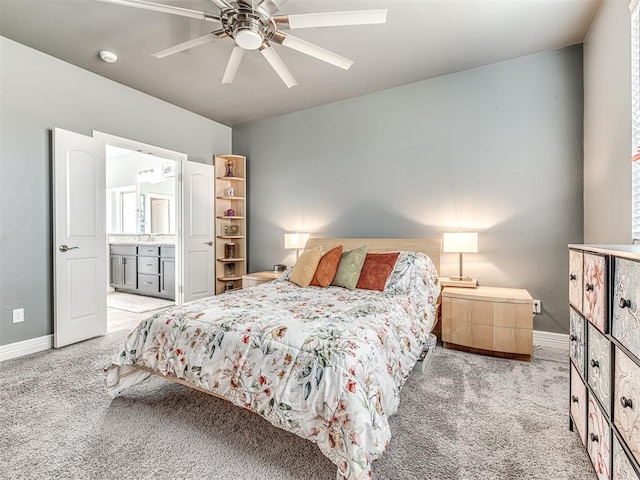 bedroom featuring light carpet, ceiling fan, baseboards, and connected bathroom