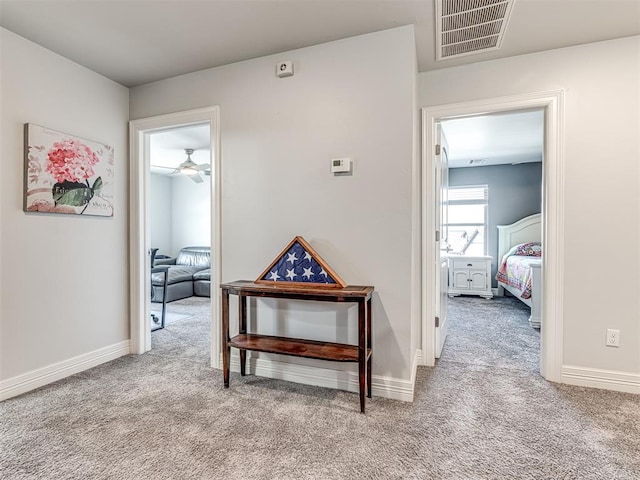 hallway featuring visible vents, baseboards, and carpet flooring