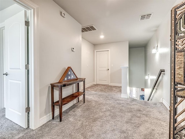 hall with an upstairs landing, visible vents, baseboards, and carpet