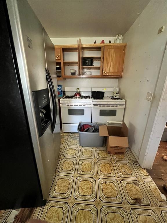 707 W Washington St, Tecumseh, OK 74873 - kitchen with stainless steel fridge with ice dispenser, tile patterned floors, open shelves, and white gas range oven