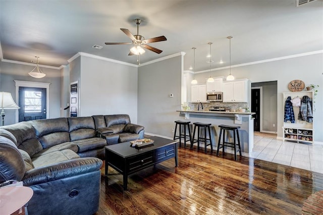living room with wood finished floors, ceiling fan, baseboards, and visible vents