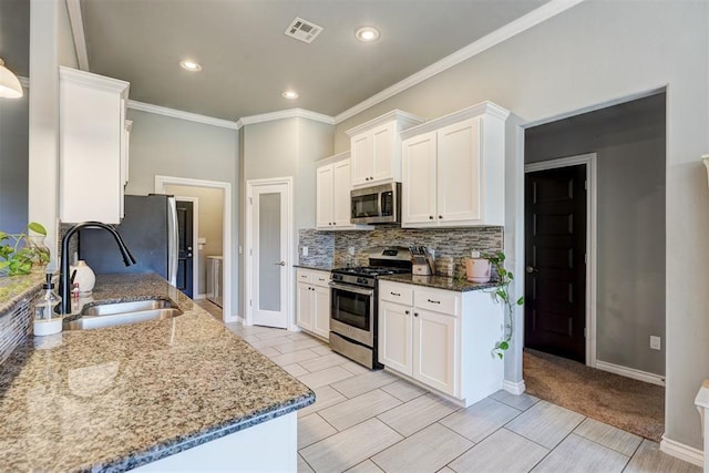 kitchen featuring white cabinets, visible vents, a sink, stainless steel appliances, and backsplash