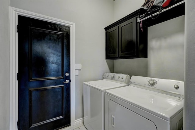 clothes washing area featuring washing machine and dryer, baseboards, and cabinet space