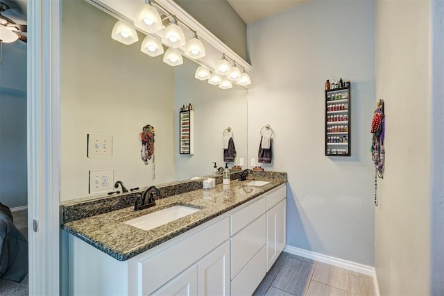full bathroom featuring a sink, baseboards, and double vanity