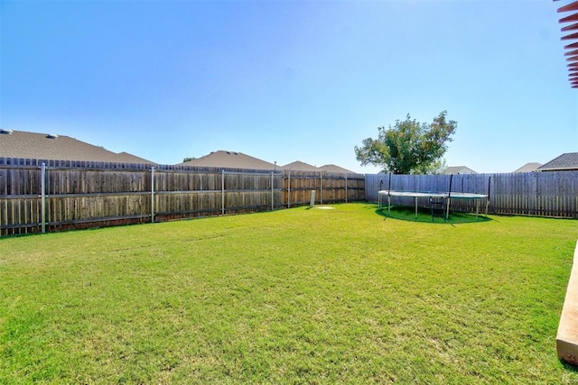view of yard with a fenced backyard and a trampoline