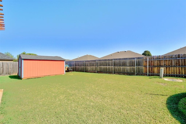 view of yard featuring a storage shed, a fenced backyard, and an outdoor structure
