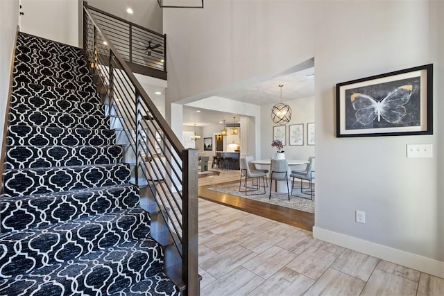 13120 Knight Island Dr, Oklahoma City, OK 73142 - staircase featuring baseboards, a chandelier, a towering ceiling, and wood tiled floor