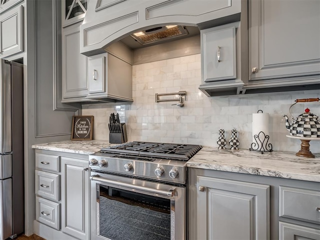 kitchen with stainless steel appliances, gray cabinetry, arched walkways, and tasteful backsplash