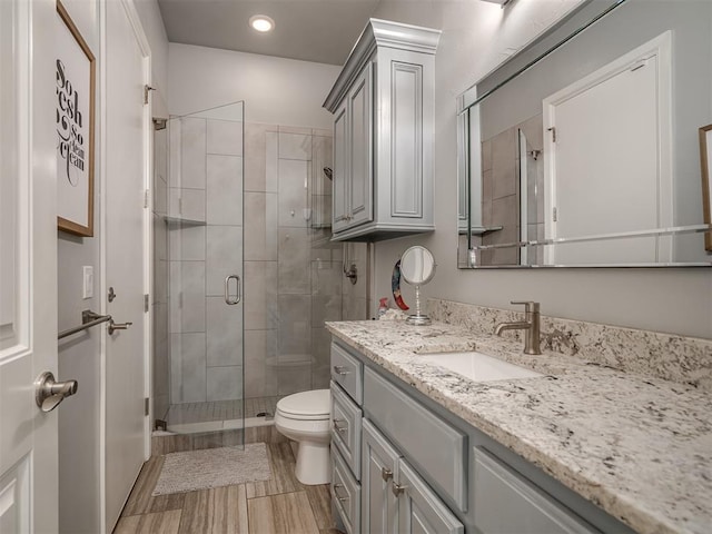 bathroom with vanity, recessed lighting, a shower stall, and toilet