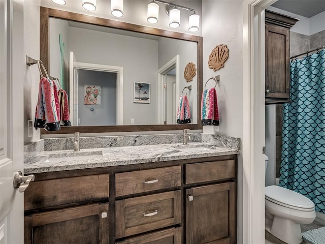 full bath with a sink, a shower with shower curtain, double vanity, and toilet
