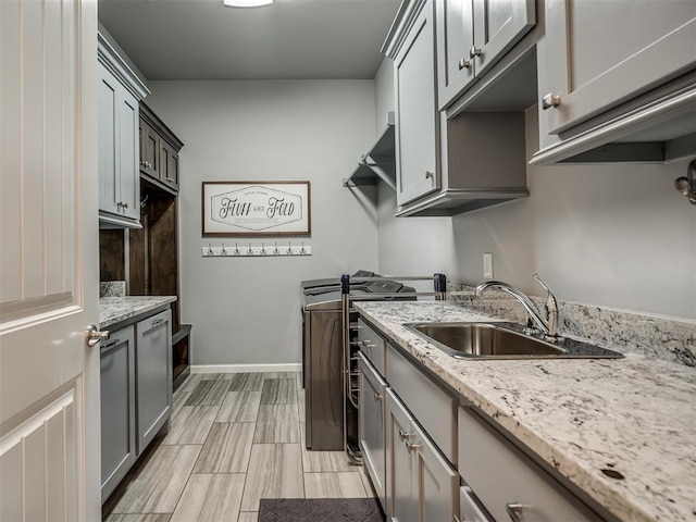 kitchen with baseboards, a sink, stove, and light stone counters