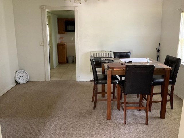 dining room with light colored carpet, baseboards, and heating unit