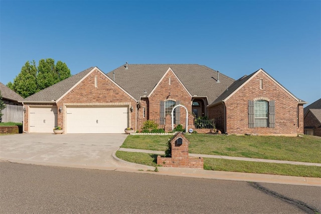 19605 Talavera Ln, Edmond, OK 73012 - view of front of house featuring roof with shingles, a front lawn, brick siding, an attached garage, and driveway