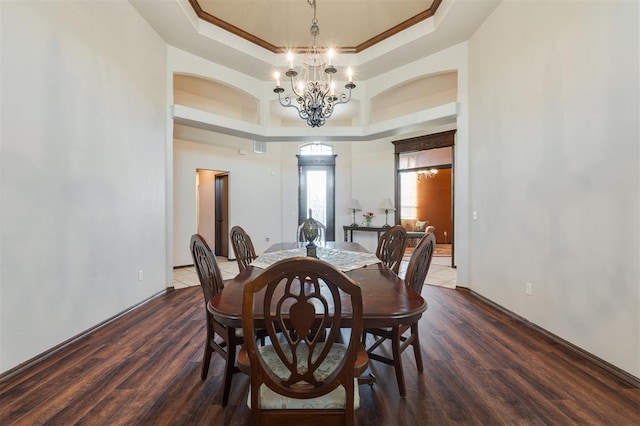 19605 Talavera Ln, Edmond, OK 73012 - dining room featuring arched walkways, ornamental molding, a chandelier, a tray ceiling, and wood finished floors