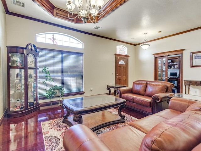 living area featuring a chandelier, ornamental molding, baseboards, and wood finished floors