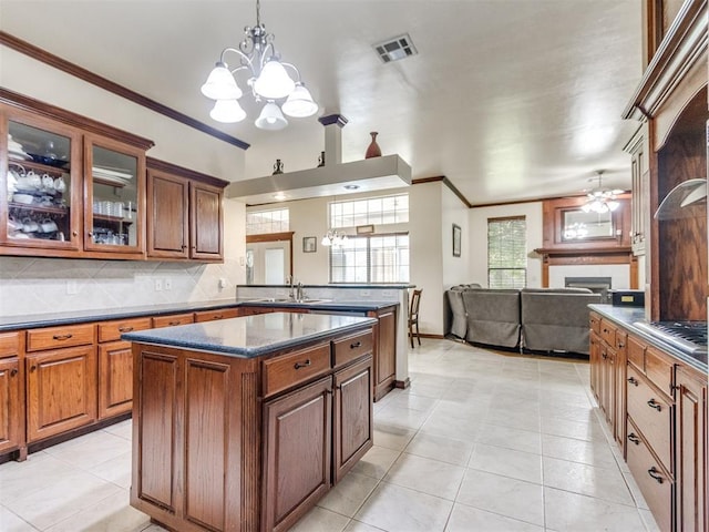 kitchen with a sink, a chandelier, crown molding, ceiling fan, and a fireplace