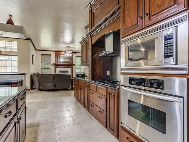 kitchen featuring stainless steel appliances, a ceiling fan, a fireplace, light tile patterned flooring, and crown molding