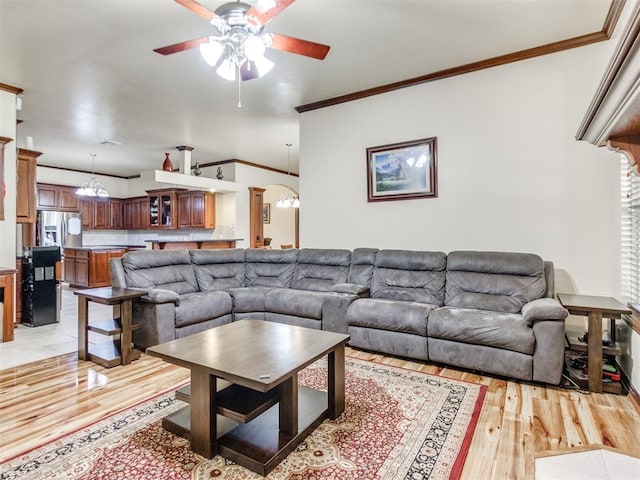 living area featuring a ceiling fan, light wood-style flooring, ornamental molding, and plenty of natural light