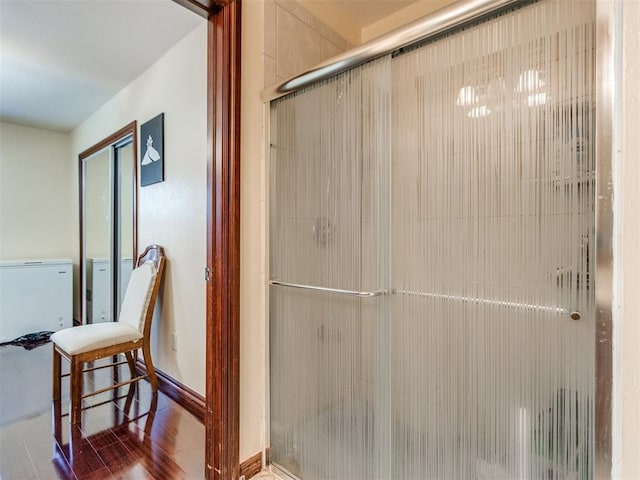 full bathroom featuring a shower stall, baseboards, and wood finished floors
