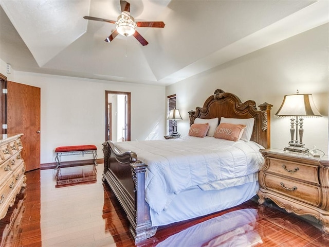 bedroom featuring lofted ceiling, wood finished floors, a tray ceiling, and ceiling fan