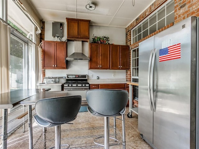 kitchen with appliances with stainless steel finishes, wall chimney exhaust hood, and light countertops
