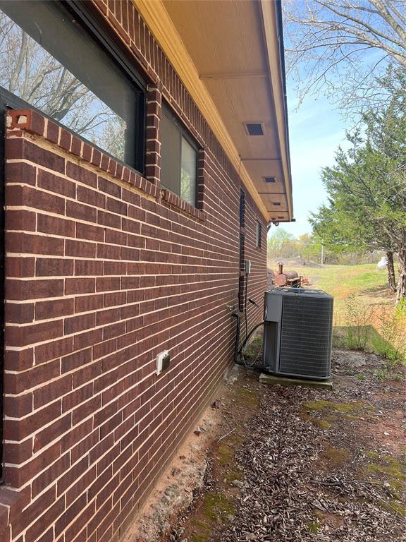 view of side of home with brick siding and central air condition unit