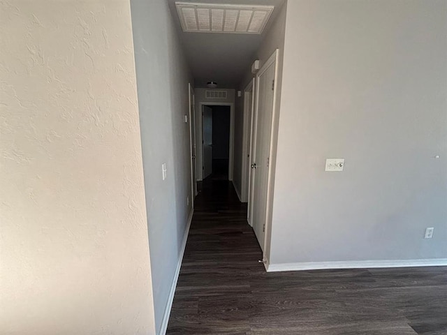 hallway featuring visible vents, baseboards, and dark wood-type flooring