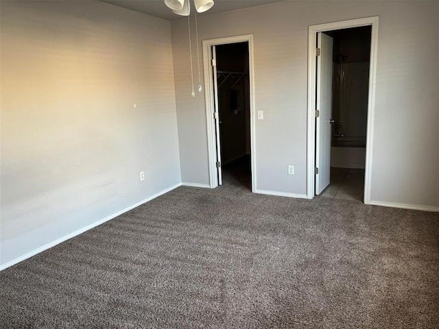 unfurnished bedroom with a walk in closet, carpet floors, baseboards, a closet, and ensuite bath