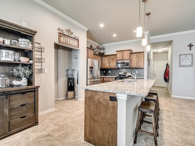207 Lyla Glen St, Washington, OK 73093 - kitchen featuring appliances with stainless steel finishes, ornamental molding, tasteful backsplash, brown cabinetry, and a kitchen breakfast bar