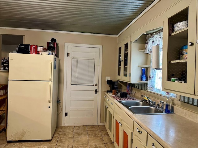 712 1st St, Maysville, OK 73057 - kitchen featuring a sink, freestanding refrigerator, glass insert cabinets, light countertops, and ornamental molding