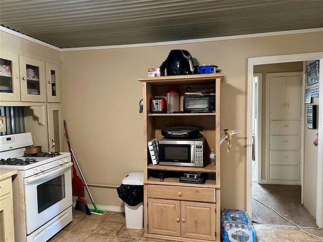 712 1st St, Maysville, OK 73057 - kitchen featuring light countertops, white range with gas stovetop, stainless steel microwave, light tile patterned flooring, and crown molding