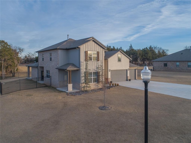 view of front of property featuring board and batten siding, driveway, a garage, and fence