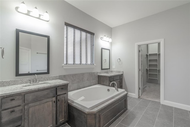full bathroom featuring a bath, two vanities, a sink, and tile patterned floors