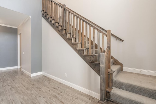stairway featuring crown molding, baseboards, and wood finished floors