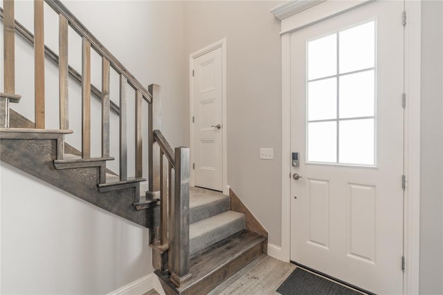 foyer with stairs, light wood-style floors, and baseboards