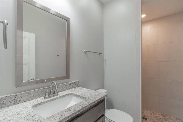 full bath with a tile shower, toilet, and vanity