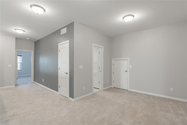 unfurnished bedroom with visible vents, baseboards, and light colored carpet