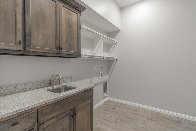 laundry room featuring electric dryer hookup, hookup for a washing machine, cabinet space, light wood finished floors, and a sink