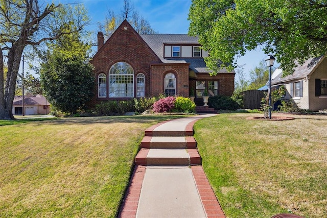 500 NW 41st St, Oklahoma City, OK 73118 - tudor-style house with roof with shingles, a front yard, brick siding, and a chimney