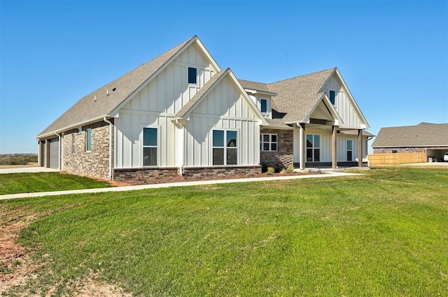 view of front of home featuring board and batten siding, a front yard, an attached garage, a shingled roof, and driveway