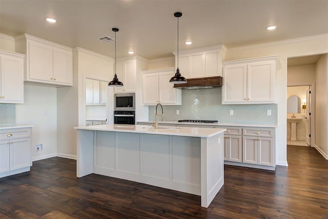 kitchen with stainless steel microwave, black oven, light countertops, visible vents, and a sink