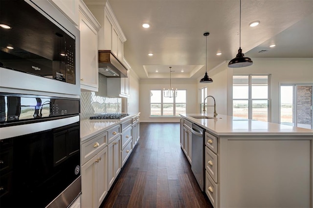 kitchen with custom exhaust hood, light countertops, black appliances, a raised ceiling, and a sink