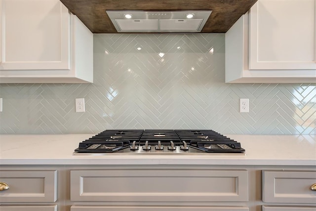 kitchen with tasteful backsplash, stainless steel gas stovetop, and white cabinetry