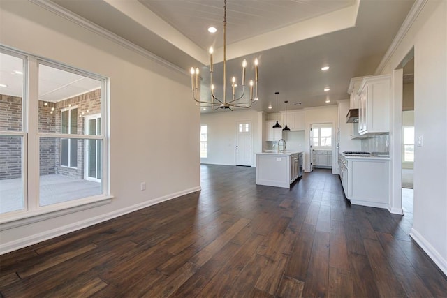 kitchen featuring an inviting chandelier, white cabinetry, dark wood-style flooring, open floor plan, and a center island with sink