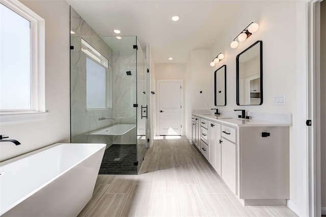 full bathroom featuring a freestanding tub, a sink, double vanity, and a stall shower