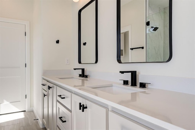 full bathroom featuring a marble finish shower, double vanity, wood finished floors, and a sink