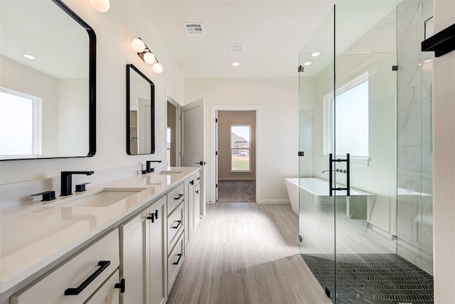 bathroom featuring a freestanding tub, visible vents, recessed lighting, a sink, and double vanity