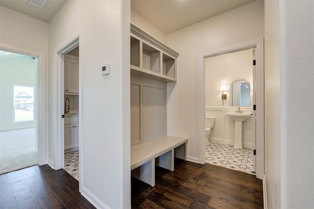 mudroom featuring a sink, dark wood-style floors, and baseboards